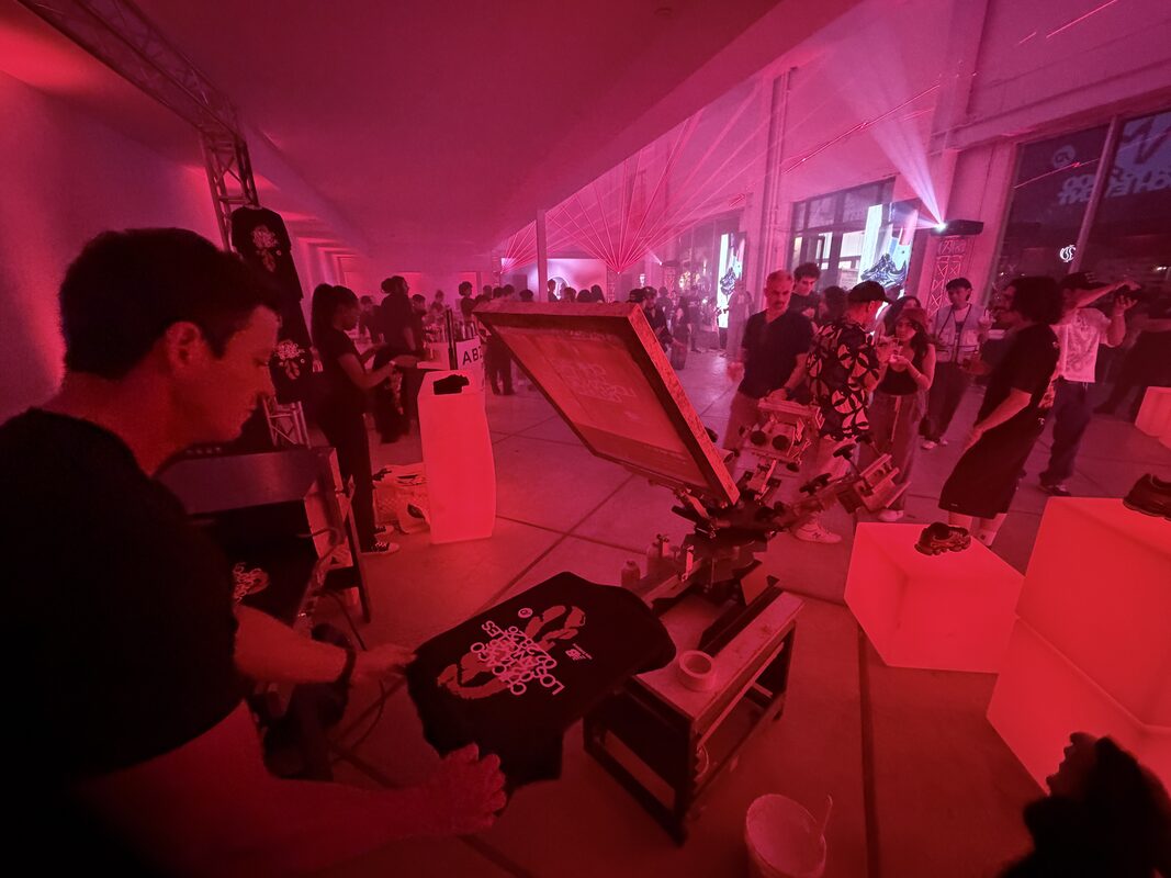 Heat press closing on a DTF transfer over a garment at a live event station