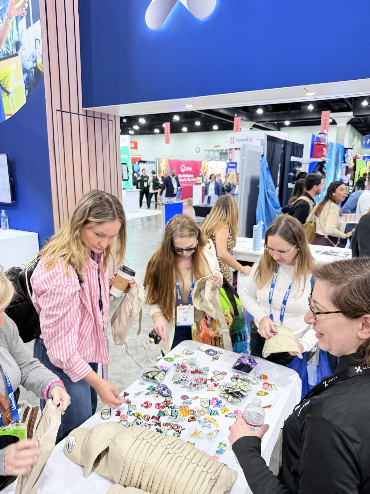 Event attendees examining decorated apparel and custom products at a vendor booth with colorful display materials